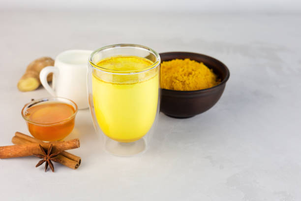 Golden milk, turmeric, honey, ginger root, cinnamon and other ingredients on grey background. Masala Haldi Doodh.