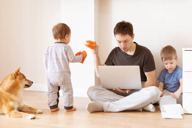 Father working at home office while the kids are playing. Home office and telecommuting concept stock photo
