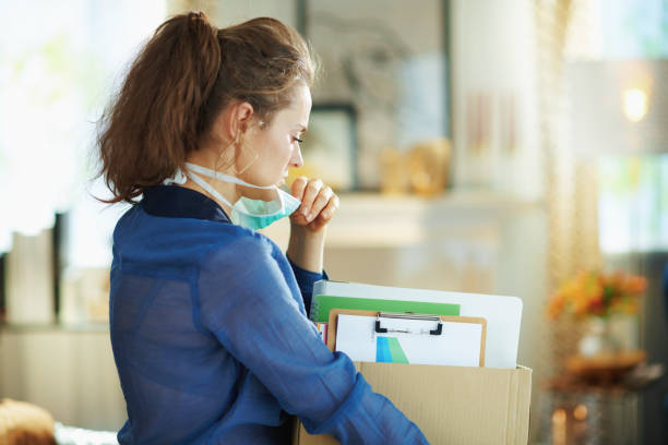 istock modern woman with mask transporting stuff to home office 1214479359