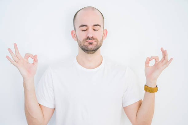 istock Young bald man over white isolated background relax and smiling with eyes closed doing meditation gesture with fingers. Yoga concept. 1214479772