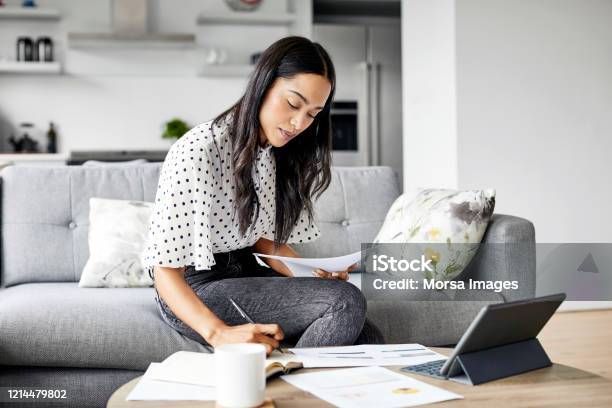 Woman Analyzing Documents While Sitting At Home Stock Photo - Download Image Now - Working At Home, Finance, Savings