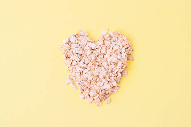 flocons d’avoine sur un fond jaune. concept d’alimentation saine. - oatmeal oat heart shape rolled oats photos et images de collection
