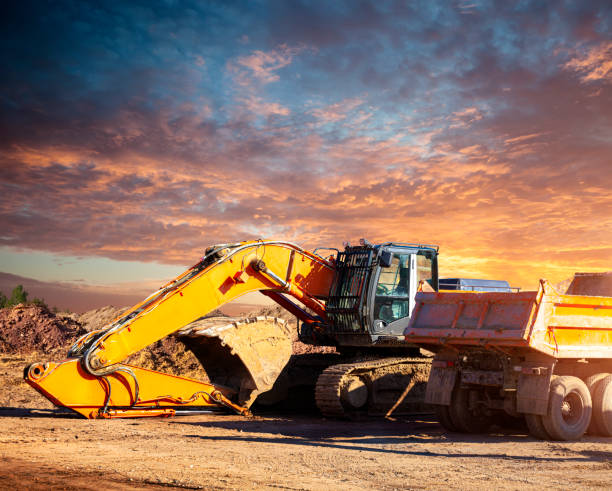 istock Excavator and dump truck car at construction site in the evening 1214482737