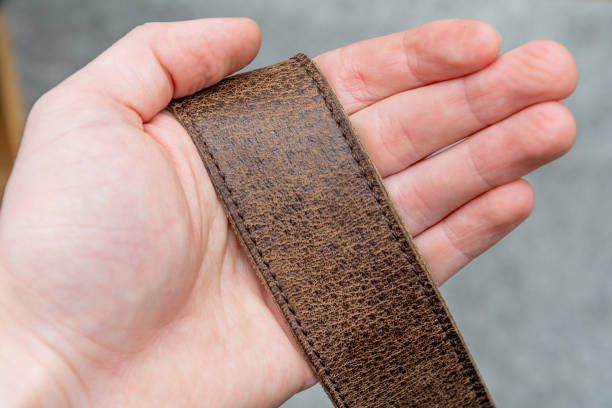 Holding natural cow leather strap in hand dark brown color Holding natural cow leather strap on hand dark brown color leather pocket clothing hide stock pictures, royalty-free photos & images