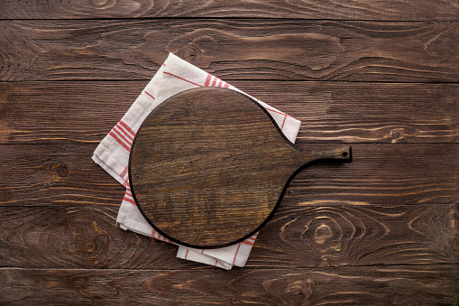 Wooden board and kitchen napkin on wooden background