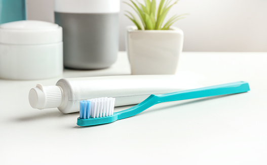 Plastic toothbrush and toothpaste in bathroom on grey background