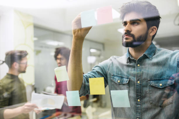 istock Businessman brainstorming notes on a glass wall in an office 1214485477