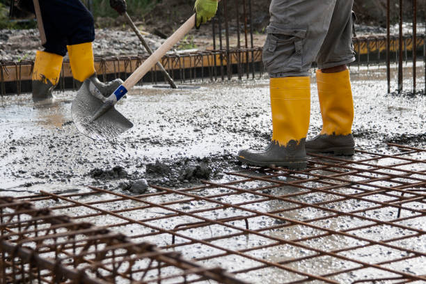 bricklayers who level the freshly poured concrete to lay the foundations of a building stock photo