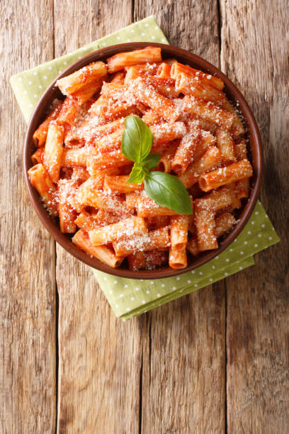 classic tortiglioni pasta recipe with parmesan basil in tomato sauce close-up in a plate. vertical top view - basil bowl cooked cheese imagens e fotografias de stock