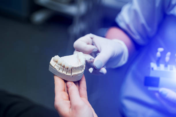 istock Doctor shows on a plastic jaw sample or model different methods of teeth treatment. 1214490070