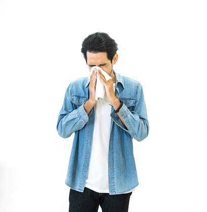 Young Asian handsome man in casual jeans dress having flu season and sneeze using paper tissues prevent spreading virus and bacteria isolated on white background, Health and illness concepts.