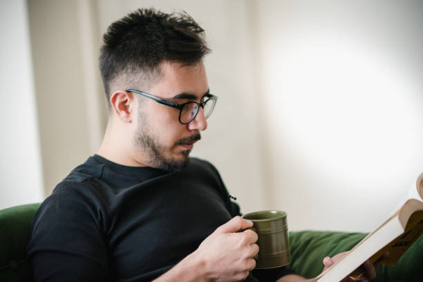 istock Young Adult Reading Book and Having Coffee 1214490506