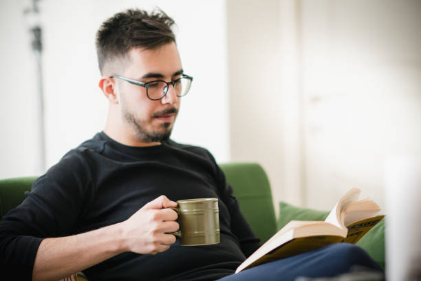 istock Young Adult Reading Book and Having Coffee 1214490522