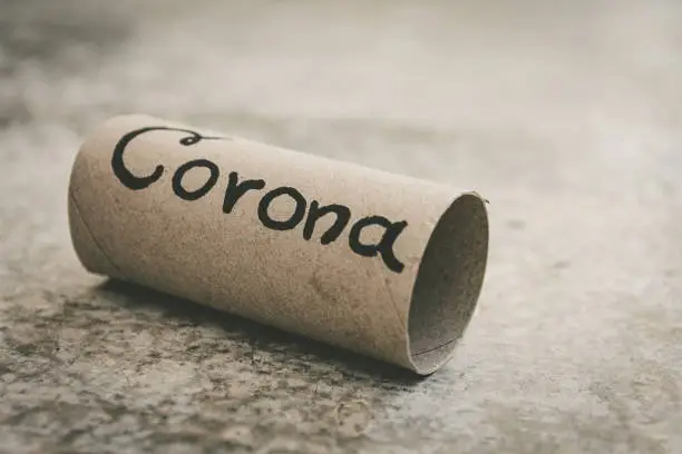 last piece of toilet paper roll on the ground with hand drawn word corona in selective focus