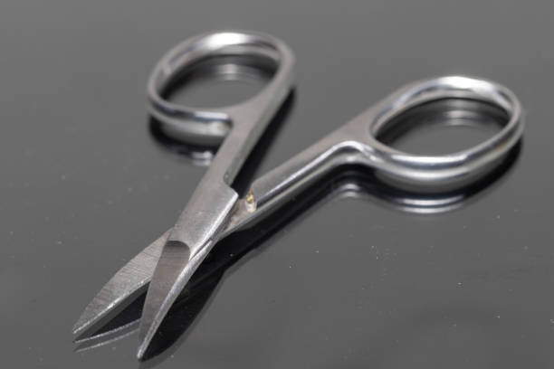 Close-up of open manicure scissors with a reflection. These scissors are being used to cut nails from fingers and toes