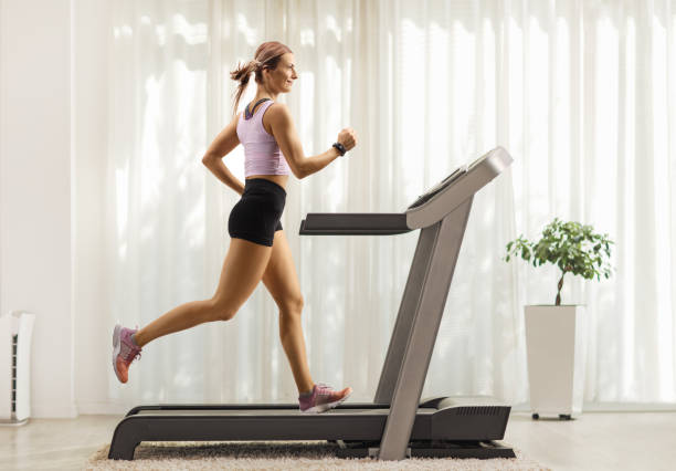 fit woman running on a treadmill at home - running women jogging profile imagens e fotografias de stock