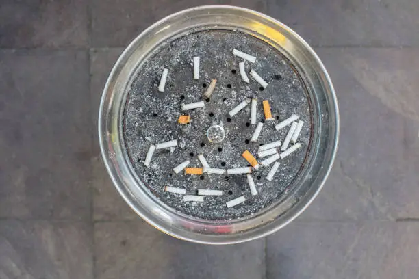 Discarded cigarette butts close up in an ashtray. Full frame image
