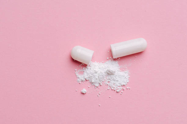 istock Drug capsule broken in half with powder ingredient sprinkled over nearby surface 1214495791