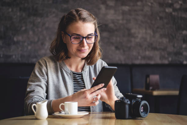 istock Young woman seated in a cafeteria using her mobile 1214495995