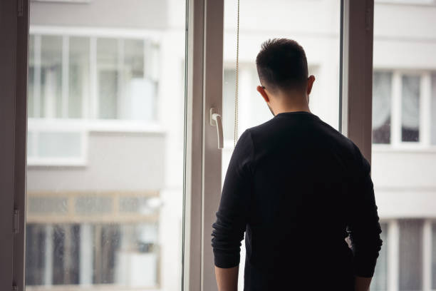 istock Man looking through the apartment window 1214496794