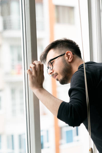 istock Man looking through the apartment window 1214496953