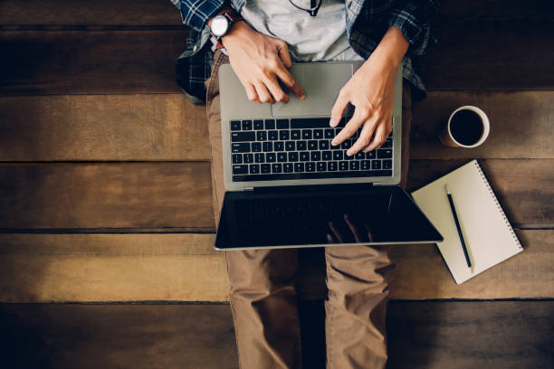 istock businessman sitting on wooden floor with coffee cup and note book using laptop working at home to send and send reply to email Message customer service 1214499301