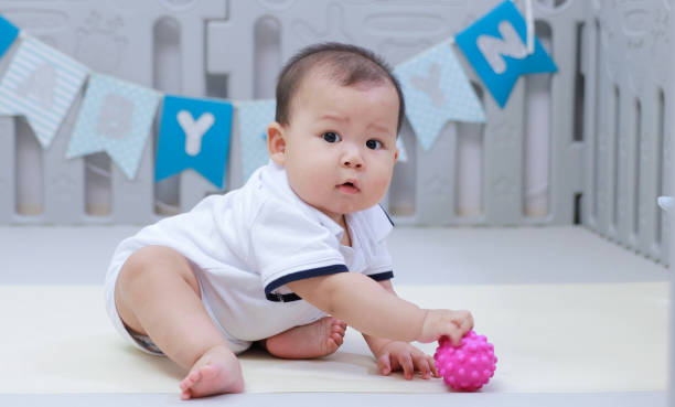 istock infant sitting play with ball in nursery 1214499847