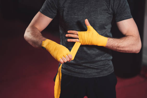 istock Unrecognizable boxer wrapping his hands with yellow hand wraps 1214503710