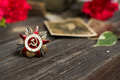 Victory Day.Selective focus on the Order of the red star with the Russian inscription Patriotic war on a wooden background with red carnations.Celebration on may 9.Memorial day.Greeting card.copyspace