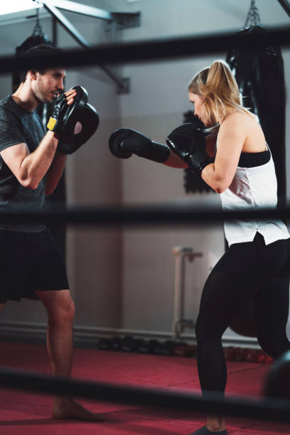istock Boxing trainer sparring with his female client 1214504139