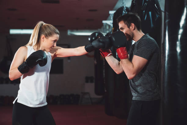 istock Woman giving punches at her boxing trainer 1214504195