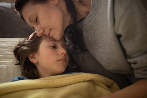 istock Boy lying sick on sofa and his mother taking care for him 1214507347
