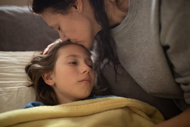 istock Boy lying sick on sofa and his mother taking care for him 1214507375