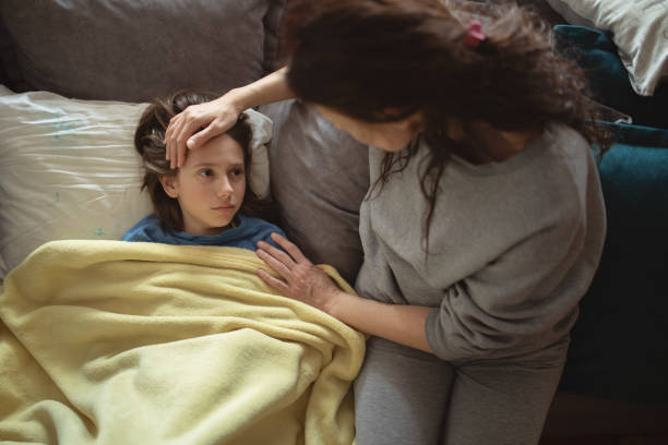 istock Boy lying sick on sofa and his mother taking care for him 1214507388