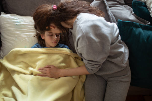 istock Boy lying sick on sofa and his mother taking care for him 1214507435