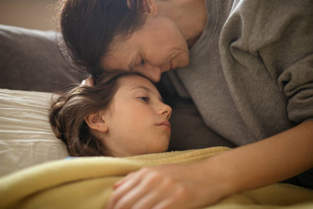 istock Boy lying sick on sofa and his mother taking care for him 1214507452