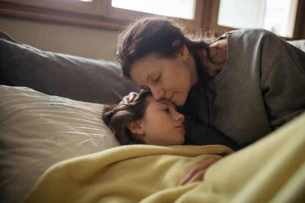 istock Boy lying sick on sofa and his mother taking care for him 1214507453