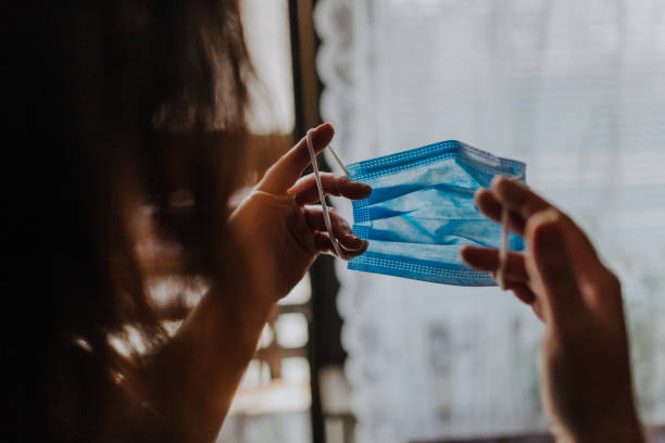 Woman is holding a COVID-19 anti-coronavirus mask as protection against infection Woman is holding a COVID-19 anti-coronavirus mask as protection against infection protective-face-mask stock pictures, royalty-free photos & images