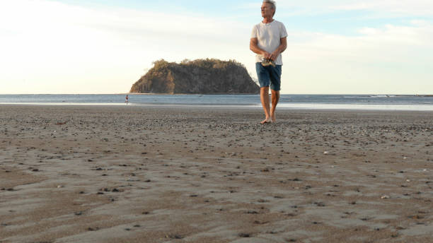 istock Man walks along beach at sunrise 1214508202