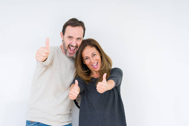 istock Beautiful middle age couple in love over isolated background approving doing positive gesture with hand, thumbs up smiling and happy for success. Looking at the camera, winner gesture. 1214508342