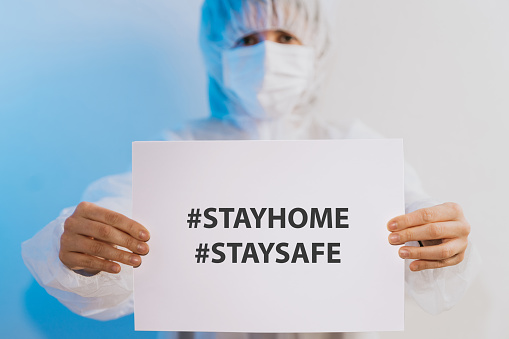 Nurse/Doctor holding a paper with a message for people to stay at home