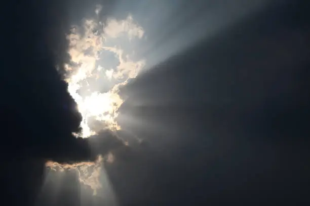 Photo of The light shone through from a dark cloud. The sun shines through the dark clouds.