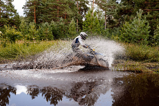 motocross rider riding a puddle in forest trail. splashes and drops of water