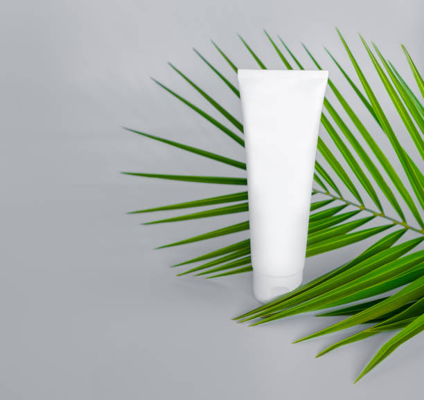 istock Mockup of a cream bottle with palm leaf. Grey background. 1214511047