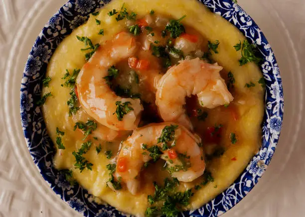 Shrimp atop of yellow grits on white plate