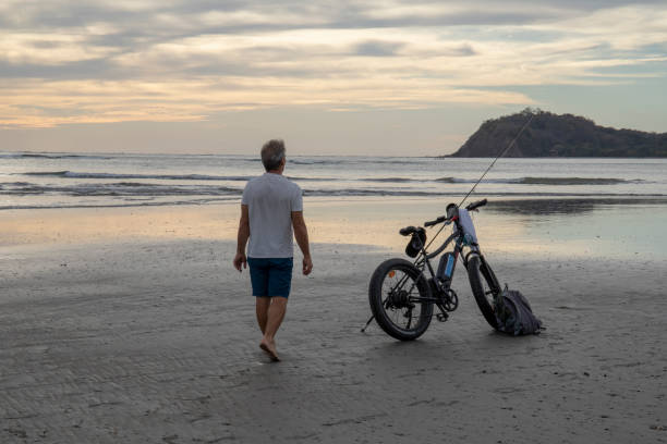 열대 해변을 걷는 전자 자전거를 가진 남자 - 16733 뉴스 사진 이미지