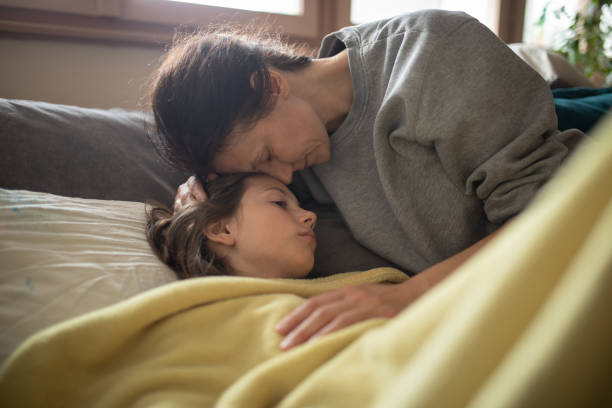 istock Boy lying sick on sofa and his mother taking care for him 1214514778