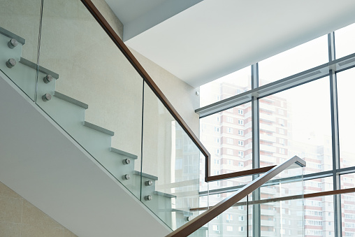 Part of staircase with railings and large window inside new contemporary business center or office building with many floors