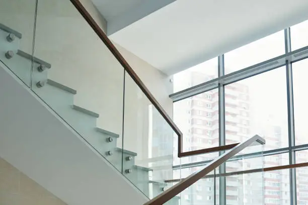 Part of staircase with railings and large window inside new contemporary business center or office building with many floors