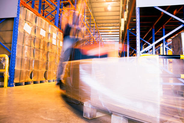 istock Motion blur of forklift driver unloading pallet goods in large warehouse. 1214517431